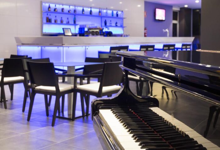 Hotel Gran Canaria Princess Adults Only piano bar. Gay-friendly hotel with elegant bar, tables, and piano. Modern design with blue lighting.