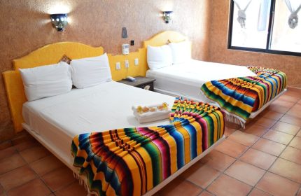 Hotel Hacienda Maria Bonita room with two beds. Gay-friendly hotel featuring colorful serape blankets, tile floors, and a warm, inviting ambiance.