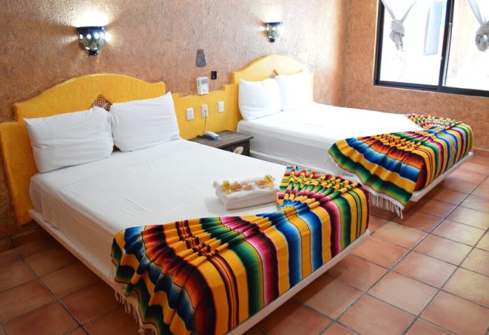 Hotel Hacienda Maria Bonita room with two beds. Gay-friendly hotel featuring colorful serape blankets, tile floors, and a warm, inviting ambiance.