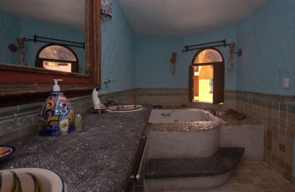 Hotel Hacienda Maria Bonita's gay-friendly bathroom. Bathtub with steps, sink, and window. A comfortable space for gay travelers.