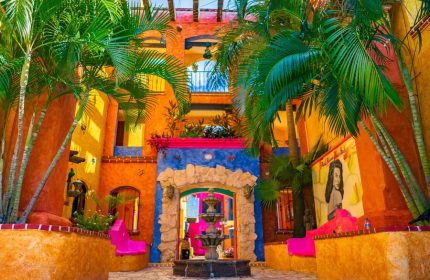 Hotel Hacienda Maria Bonita, a gay-friendly hotel. Colorful courtyard with fountain, palm trees, and Mexican architecture. Ideal for gay travel.