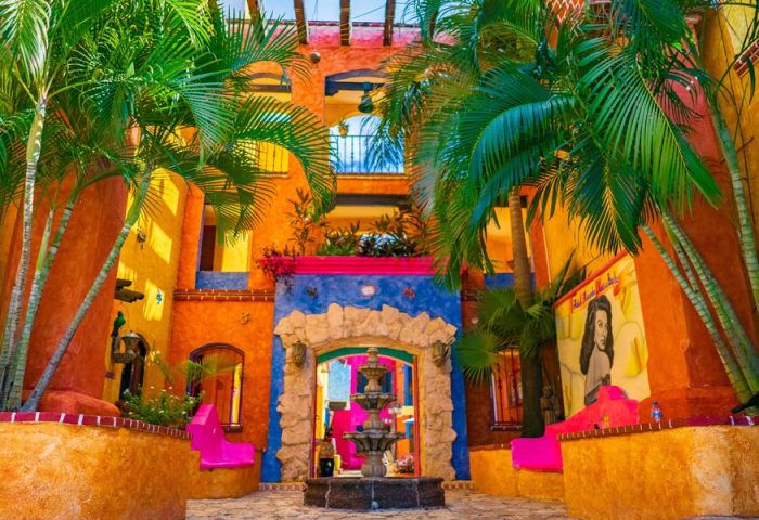 Hotel Hacienda Maria Bonita, a gay-friendly hotel. Colorful courtyard with fountain, palm trees, and Mexican architecture. Ideal for gay travel.
