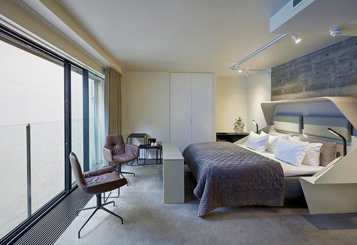 Hotel Herman K by Brøchner Hotels bedroom. Gay-friendly hotel room with a king bed, chairs, and a large window. Modern design for gay travelers.