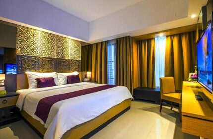 Hotel Horison Seminyak Bali gay-friendly hotel room. Bed with purple accents, TV, chair, and decorative headboard. Luxury accommodations in Bali.