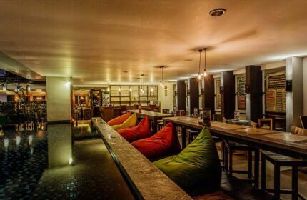 Hotel Horison Seminyak Bali interior. Gay-friendly hotel with colorful beanbags, wooden tables, and bar area. Bali travel for gay men.
