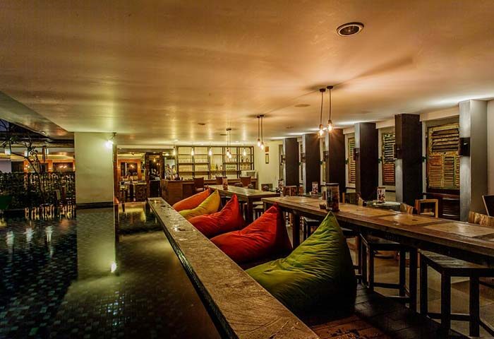 Hotel Horison Seminyak Bali interior. Gay-friendly hotel with colorful beanbags, wooden tables, and bar area. Bali travel for gay men.