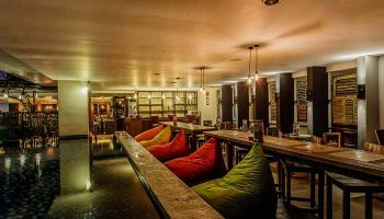 Hotel Horison Seminyak Bali interior. Gay-friendly hotel with colorful beanbags, wooden tables, and bar area. Bali travel for gay men.