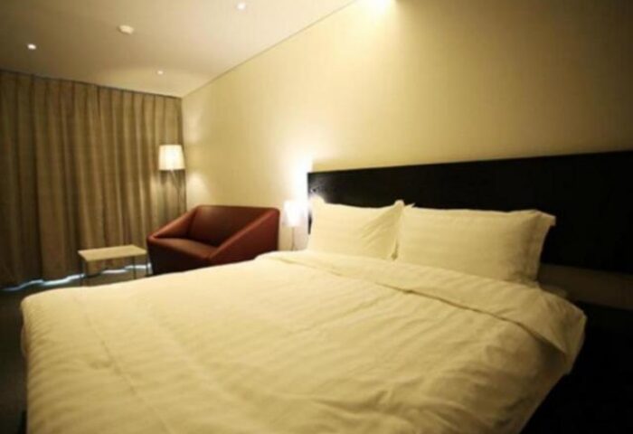 Hotel ITW room interior. Gay-friendly hotel with a large bed, chair, and soft lighting. A comfortable stay for gay travelers.
