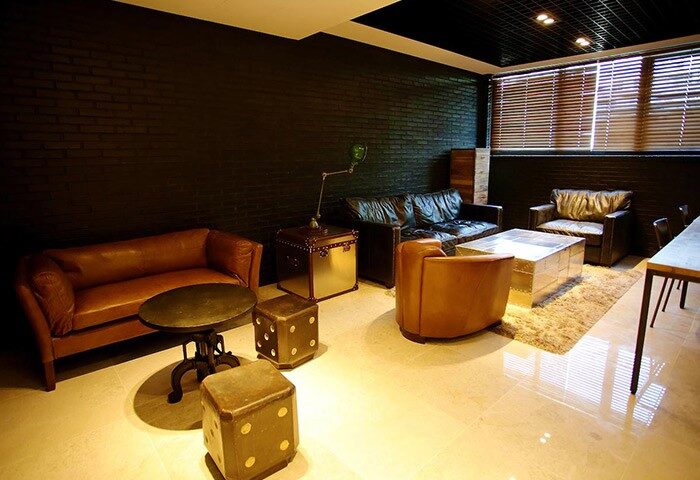 Hotel ITW, a gay-friendly hotel: Lounge area with leather sofas, armchairs, and dice-shaped stools. A stylish space for gay travelers.
