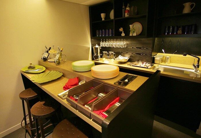 Hotel ITW's gay-friendly amenities: well-stocked breakfast bar with plates, cutlery, glasses, and drinks. Perfect for gay men's travel needs.