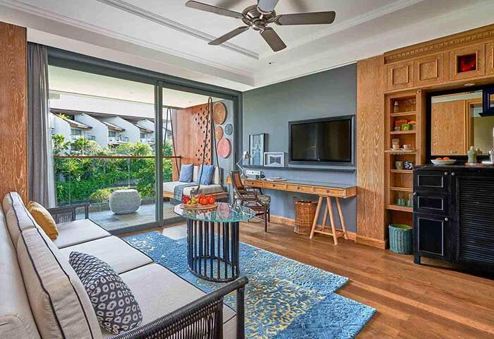 Hotel Indigo Bali Seminyak Beach suite. Living area with sofa, desk, TV, balcony. Gay-friendly hotel, stylish interior design.