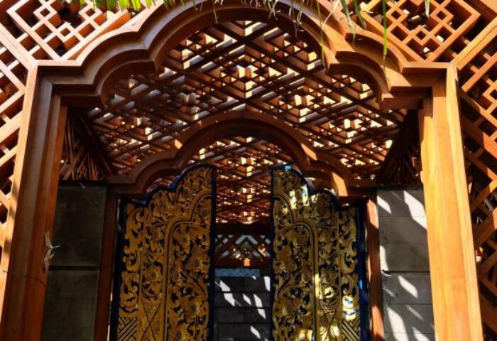 Hotel Indigo Bali Seminyak Beach's ornate wooden entrance. Carved details and geometric patterns create a welcoming gateway to this gay-friendly hotel.