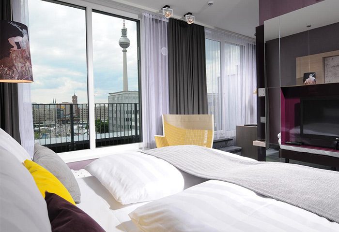 Hotel Indigo Berlin-Alexanderplatz room with TV Tower view. Gay-friendly hotel bedroom interior. Modern design, comfortable for gay travelers.