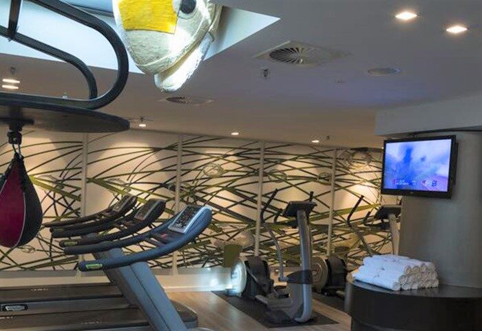 Hotel Indigo Berlin-Alexanderplatz gym. Gay-friendly hotel fitness center with treadmills, punching bag, and TV. Modern design.