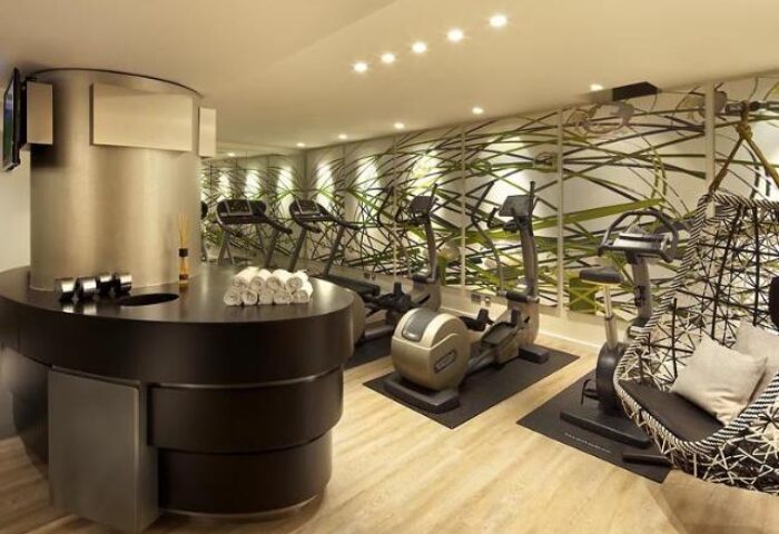 Hotel Indigo Berlin-Alexanderplatz gym. Gay-friendly hotel fitness center with exercise equipment and a decorative chair. Wellness for gay travelers.