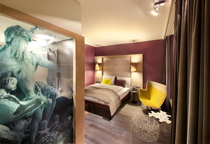Hotel Indigo Berlin-Alexanderplatz room. Gay-friendly hotel with modern design, shower art, comfy bed, and a stylish yellow chair. Perfect for gay travel.