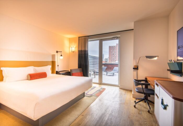 Hotel Indigo Lower East Side bedroom with balcony. Gay-friendly hotel featuring a king-sized bed, desk, and city view. Modern design.