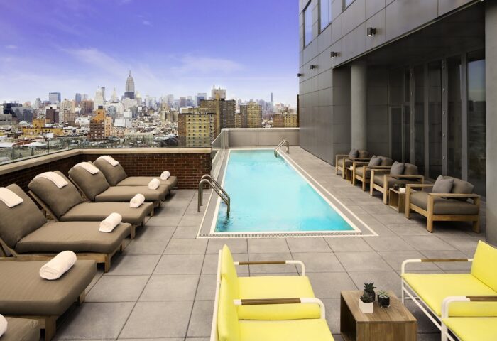 Rooftop pool at Hotel Indigo Lower East Side, a gay-friendly hotel. NYC skyline view, lounge chairs, and modern design. Perfect for gay travel.