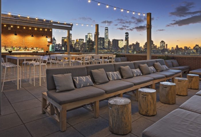 Hotel Indigo Lower East Side rooftop bar at dusk. Gay-friendly hotel with city views, seating, and string lights. A perfect spot for gay travel.