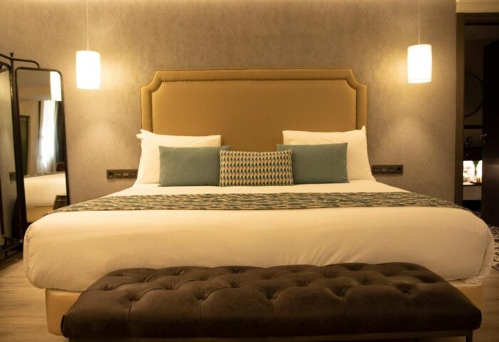 Hotel Indigo Madrid Gran Via gay-friendly hotel room. King bed, stylish headboard, bench, mirror, and modern lighting. Perfect for gay travel.