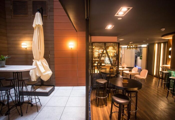 Hotel Indigo Madrid Gran Via gay-friendly hotel bar. Outdoor seating with umbrella, tables, and stools. Interior view of bar area.