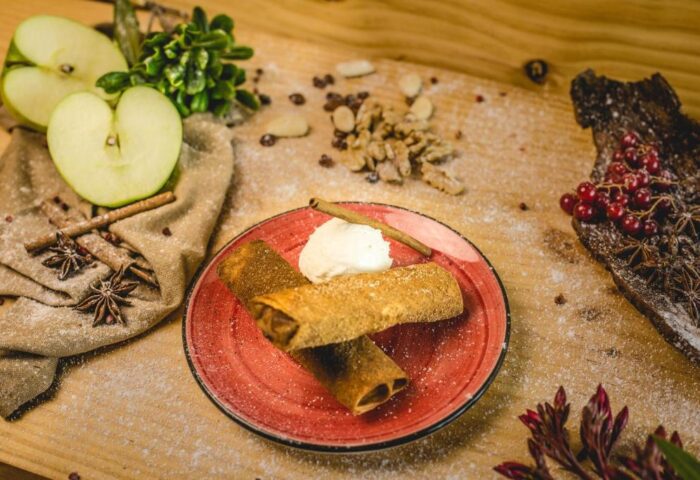 Hotel Indigo Madrid Gran Via: Delicious dessert featuring rolled crepes with ice cream, cinnamon, apple, and walnuts on a red plate.