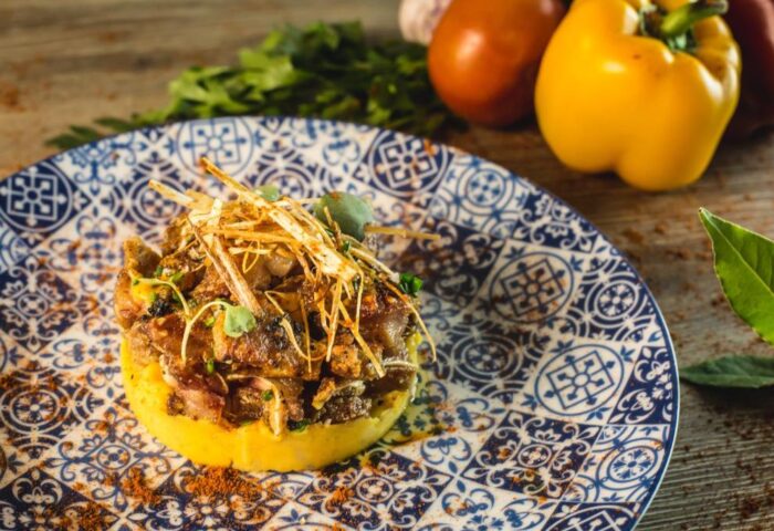 Gourmet dish at Hotel Indigo Madrid Gran Via, a gay-friendly hotel. Food presentation with meat, potatoes, and vegetables on a patterned plate.