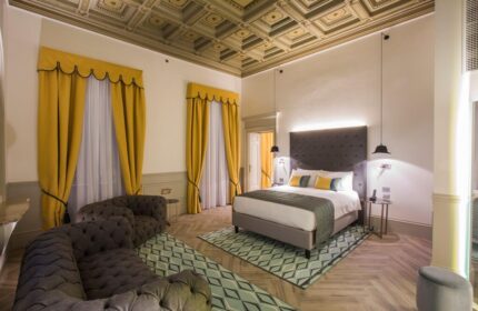 Hotel Indigo Milan Corso Monforte room. Elegant design, yellow curtains, patterned ceiling & rug. Gay-friendly hotel for discerning travelers.