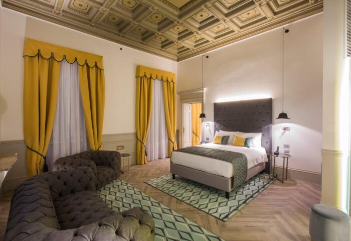 Hotel Indigo Milan Corso Monforte room. Elegant design, yellow curtains, patterned ceiling & rug. Gay-friendly hotel for discerning travelers.
