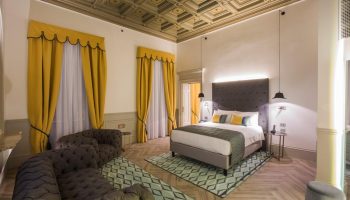 Hotel Indigo Milan Corso Monforte room. Elegant design, yellow curtains, patterned ceiling & rug. Gay-friendly hotel for discerning travelers.