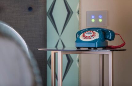 Hotel Indigo Milan Corso Monforte: Retro blue telephone on a small table. Gay-friendly hotel room detail with vintage design elements.