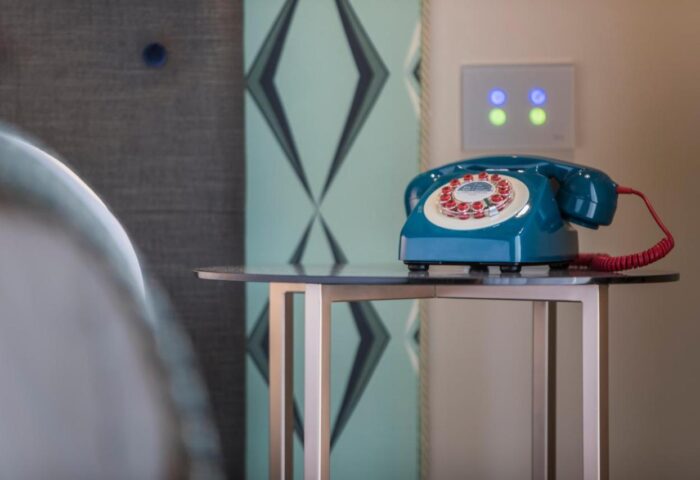 Hotel Indigo Milan Corso Monforte: Retro blue telephone on a small table. Gay-friendly hotel room detail with vintage design elements.
