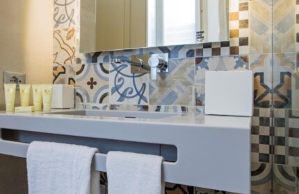 Hotel Indigo Milan Corso Monforte gay-friendly hotel bathroom. Sink with toiletries, colorful tiles, and white towels. Modern design.