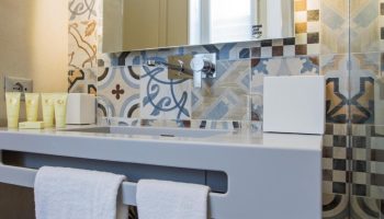 Hotel Indigo Milan Corso Monforte gay-friendly hotel bathroom. Sink with toiletries, colorful tiles, and white towels. Modern design.
