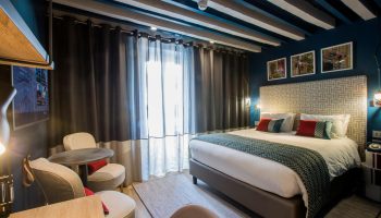 Hotel Indigo Milan Corso Monforte, gay-friendly hotel room. Bed, chairs, and blue walls. Stylish design for gay travelers.
