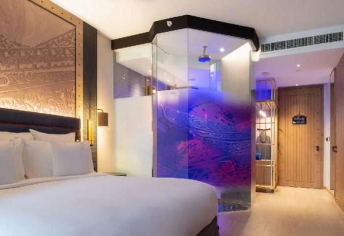 Hotel Indigo Phuket Patong bedroom. Gay-friendly hotel room with bed, glass shower, and wood door. Modern design for gay travelers.