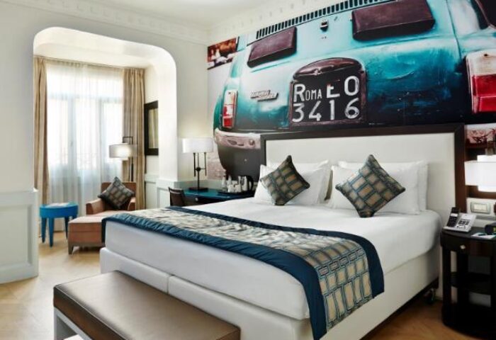 Hotel Indigo Rome St. George bedroom. Gay-friendly hotel room featuring a bed with a vintage car mural. Modern design, comfortable stay.
