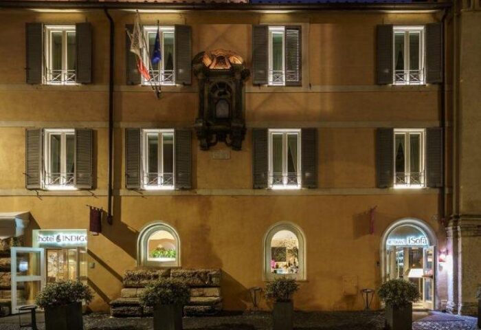 Facade of Hotel Indigo Rome - St. George, a gay-friendly hotel. The building has windows with shutters and arched doorways. Night shot.