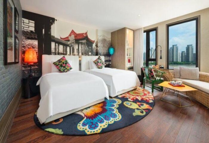Hotel Indigo Shanghai On The Bund gay-friendly hotel room. Two beds, colorful rug, city view. Modern design, comfortable space. Shanghai travel.