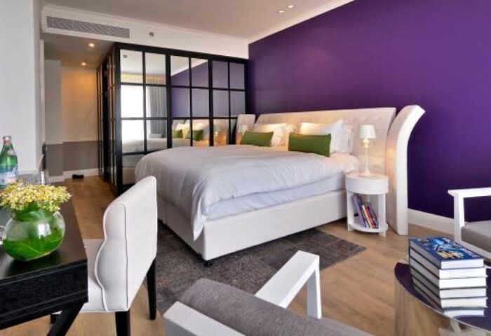 Hotel Indigo Tel Aviv-Diamond District room. Gay-friendly hotel with purple wall, white bed, and modern decor. Upscale travel for gay men.
