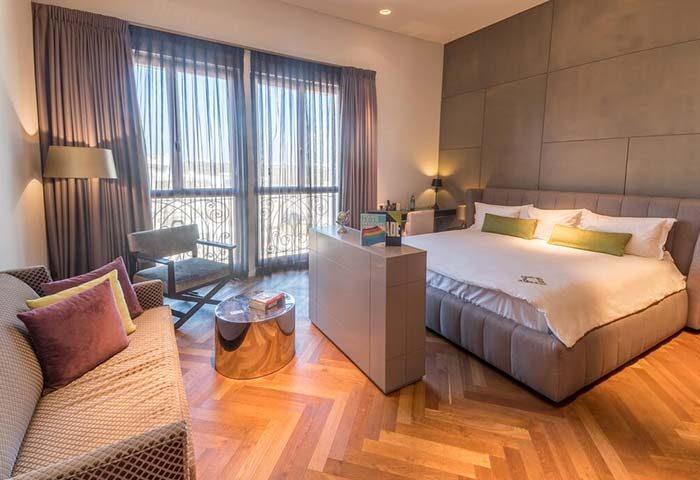 Hotel Indigo Tel Aviv Diamond District gay-friendly room. Modern design with bed, sofa, desk, and balcony. Stylish gay travel accommodation.