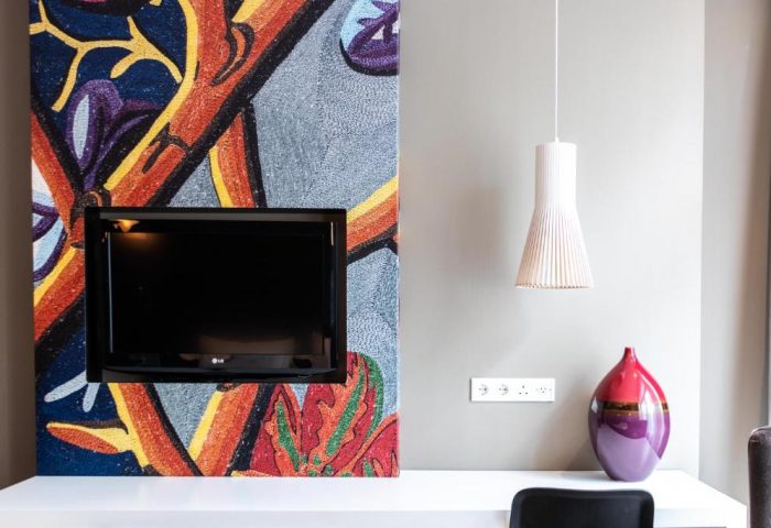 Hotel JL No76 gay-friendly hotel room detail. TV on colorful mosaic wall, pendant lamp, and vase. Modern design for gay travelers in Amsterdam.