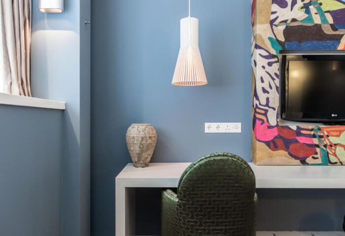 Hotel JL No76, a gay-friendly hotel. Interior view with a desk, chair, vase, and pendant lamp. Modern design in Amsterdam for gay travelers.