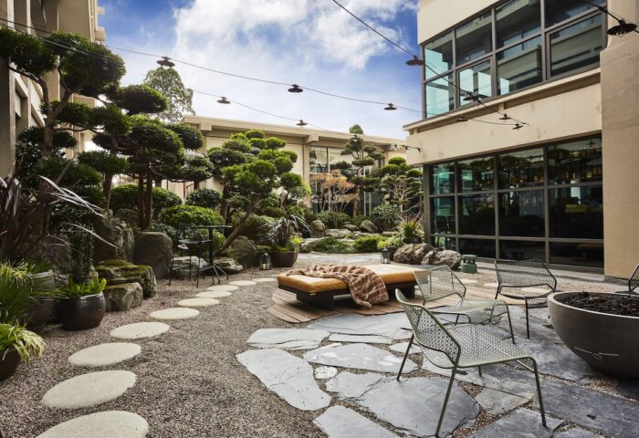 Hotel Kabuki, a gay-friendly Jdv by Hyatt hotel. Outdoor zen garden with seating, trees, and stone features. Relaxing space for gay travelers.