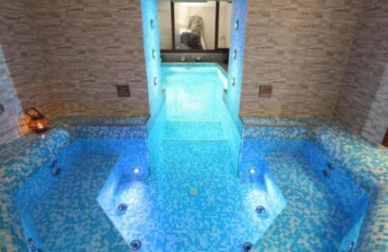 Hotel Kings Court's gay-friendly spa. Blue-tiled hot tub with jacuzzi jets, illuminated by underwater lights. Relaxing gay travel destination.