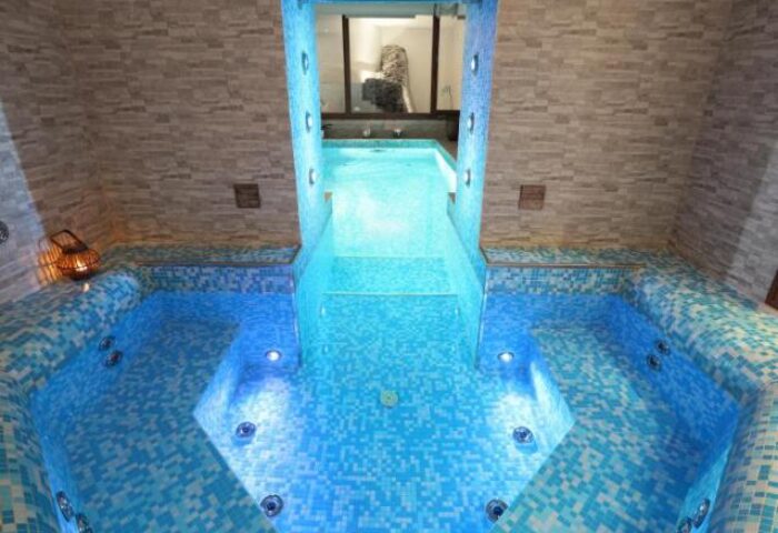 Hotel Kings Court's gay-friendly spa. Blue-tiled hot tub with jacuzzi jets, illuminated by underwater lights. Relaxing gay travel destination.