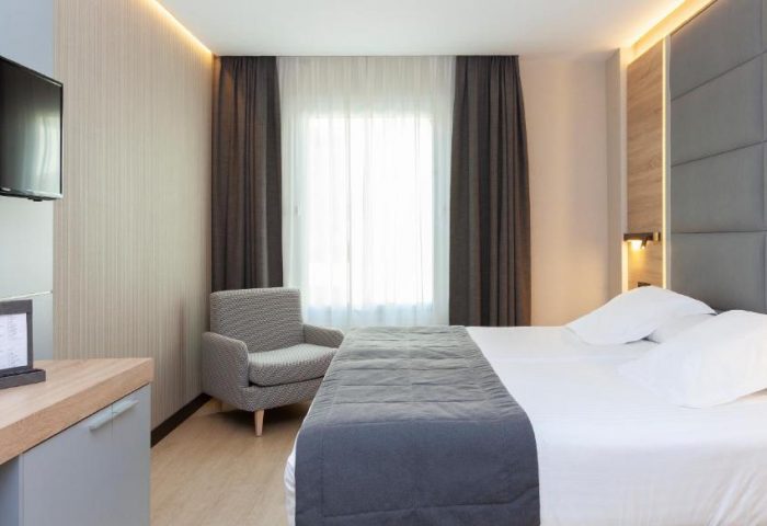 Hotel Liabeny gay-friendly room. Modern interior with a bed, chair, TV, and desk. A comfortable space for gay travelers in Madrid.