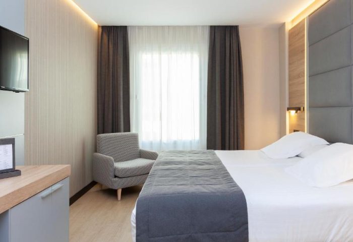 Hotel Liabeny gay-friendly room. Modern interior with a bed, chair, TV, and desk. A comfortable space for gay travelers in Madrid.