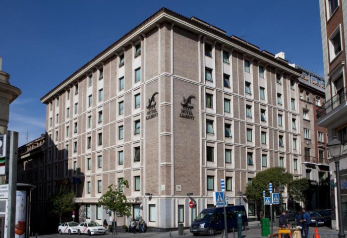 Exterior of Hotel Liabeny, a gay-friendly hotel in Madrid. The building has many windows and the hotel's logo is visible on the corner.
