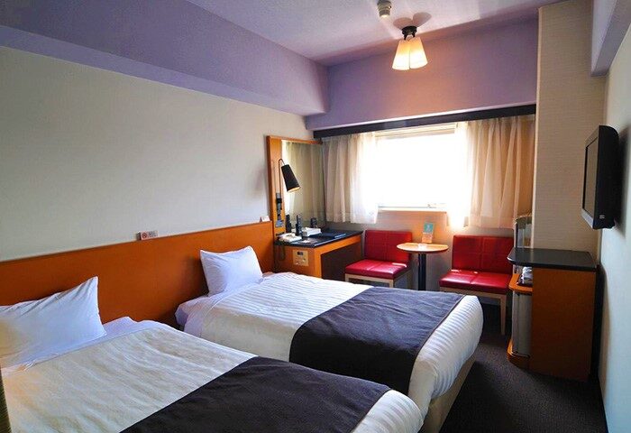 Hotel Listel Shinjuku gay-friendly hotel room with twin beds, desk, red chairs, and TV. Great for gay travel in Shinjuku, Tokyo.